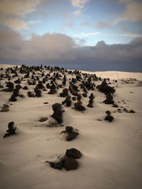 Rocks on shore against sky during sunset