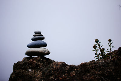 Stack of stones on rock against clear sky