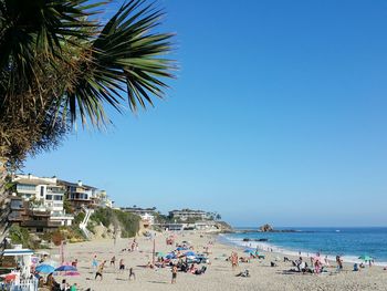 People enjoying at laguna beach against clear sky