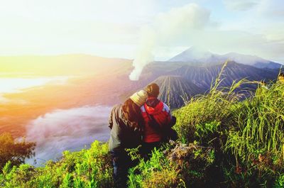 Rear view of people photographing on mountain against sky