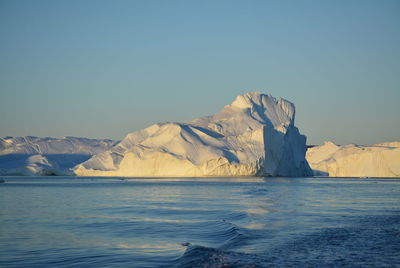 View of majestic iceberg in sea against sky