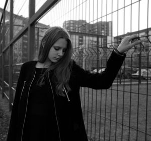 Young woman looking down while standing on railing