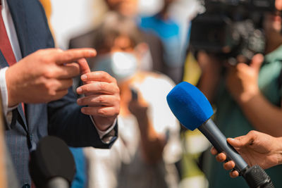 Journalists holding microphone, interviewing politician.