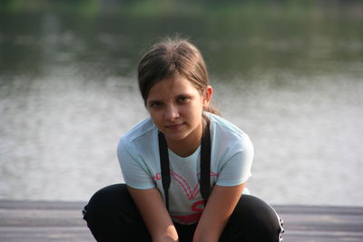 Portrait of a girl sitting against lake