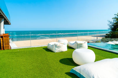 Lounge chairs by swimming pool on beach against clear sky