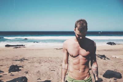 Shirtless man in sea against sky at beach