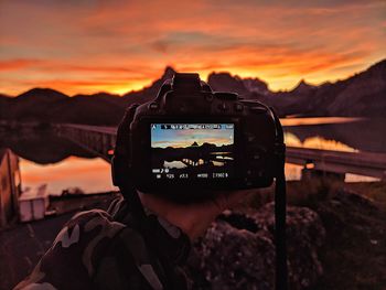 Cropped hand of man photographing during sunset