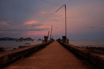 Narrow pathway along calm sea at sunset