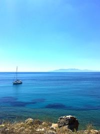 Sailboat sailing in sea against clear blue sky