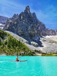 Man kayaking in lake against mountain