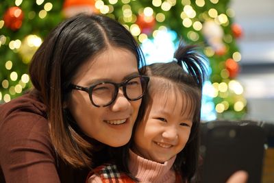 Portrait of happy mother with daughter against defocused lights