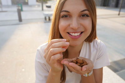 Portrait of smiling woman eating almonds outdoors