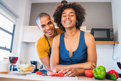 Portrait of smiling young woman eating food in kitchen at home