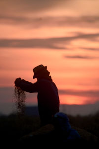 Rear view of silhouette woman standing at sunset