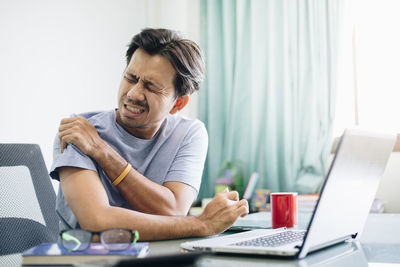 Man using mobile phone while sitting on table