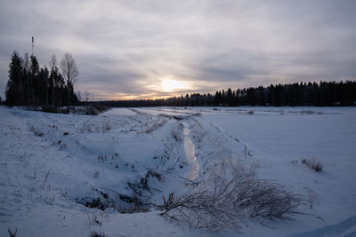Scenic view of snow covered field against sky during sunset