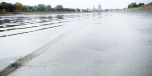 Surface level of wet sand on beach against sky