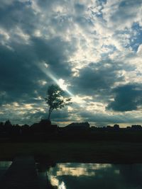 Silhouette trees by lake against sky during sunset