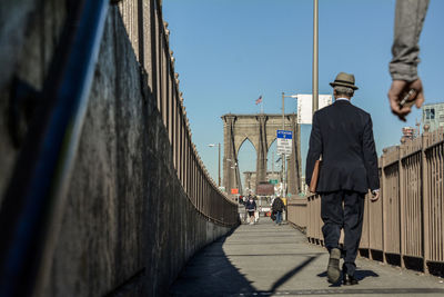 People walking at brooklyn bridge against clear sky on sunny day