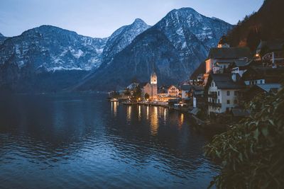 Houses by lake against snowcapped mountains