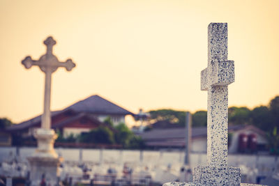 Close-up of cross at cemetery against sky