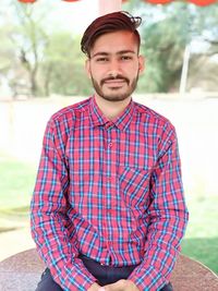 Portrait of smiling young man sitting outdoors and smart people in india