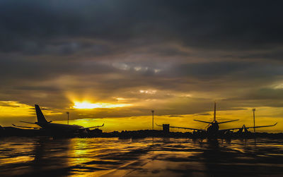 Silhouette cranes against sky during sunset