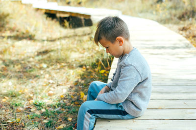 Side view of boy sitting outdoors