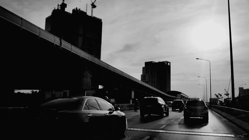 Cars on city street against sky