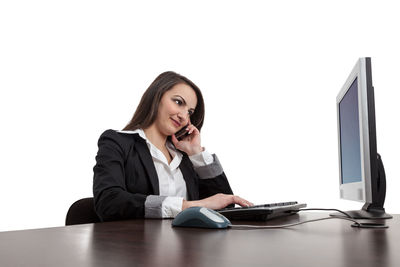 Young woman using smart phone while sitting on table