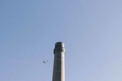 Low angle view of smoke stack against clear blue sky