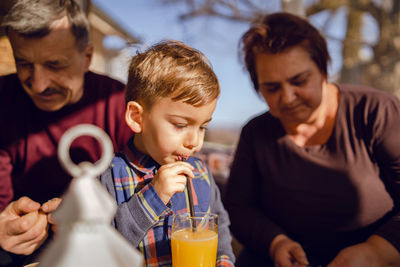 Boy drinking juice while having breakfast with grandparents at home