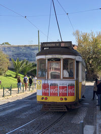 People on railroad tracks by city against sky