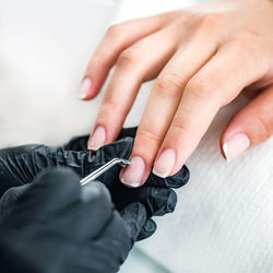 Close-up of woman doing nail art of customer at table