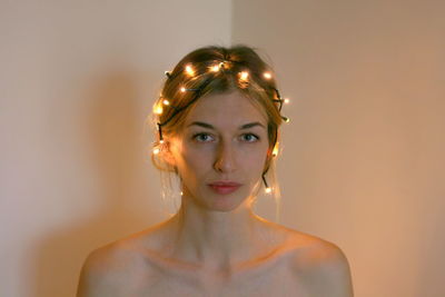 Portrait of young woman standing against wall