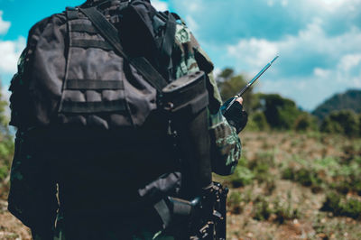 Midsection of person holding walkie-talkie while standing on land