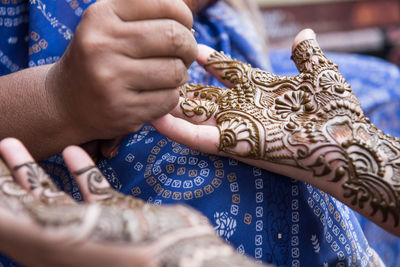 Close-up of artist making henna tattoo on bride hand