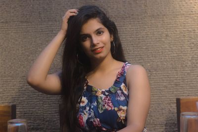 Portrait of smiling young woman sitting against wall