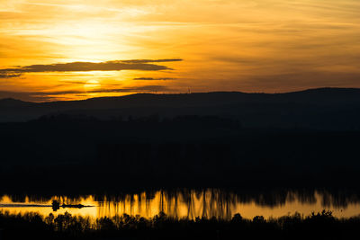 Scenic view of silhouette mountains against orange sky