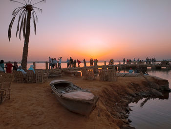 People on beach against sky during sunset