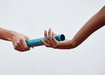 Cropped hand of woman holding bottle against white background