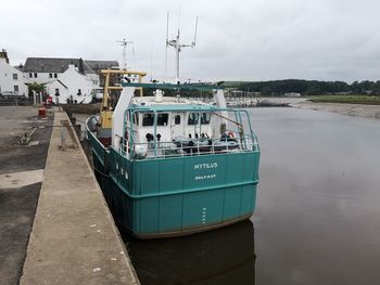 Boats moored at harbor against sky