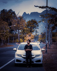 Portrait of young man standing by car