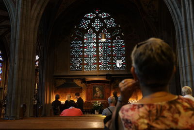 Rear view of woman sitting and praying in church