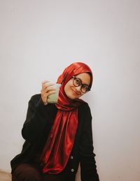 Young woman wearing sunglasses while standing against wall