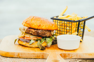 Close-up of burger served on cutting board at beach
