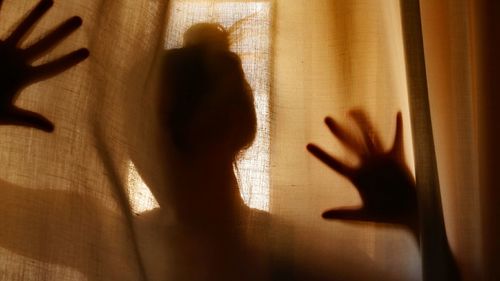 Shadow of woman hand on window at home