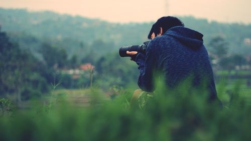 Rear view of man photographing against sky