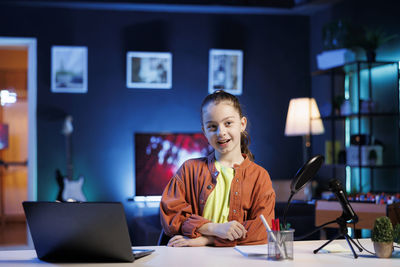 Young woman using mobile phone while sitting on table