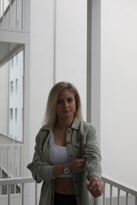 Portrait of young woman standing against building